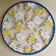 a blue and white plate topped with yellow and white flowers on top of a tile wall