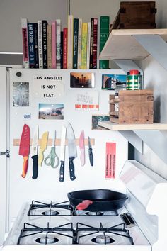 a stove top oven sitting next to a book shelf filled with books and utensils