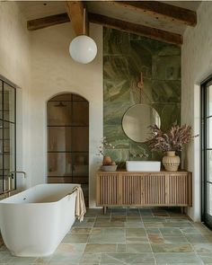 a bath room with a large tub next to a window and a mirror on the wall