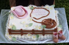 a sheet cake decorated with flowers, boots and a cowboy's hat on a table