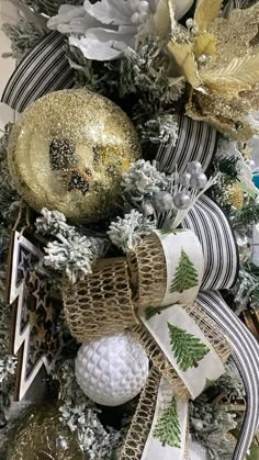 a christmas tree decorated with gold and silver ornaments, ribbons, and decorations on top of it