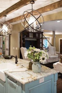 a large kitchen with an island in the middle and two chandeliers hanging from the ceiling