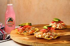 three appetizers are sitting on a cutting board next to a pink beverage bottle