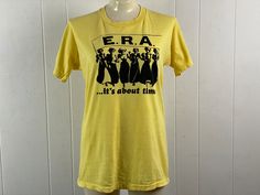 "Vintage 1970s women's lib, girl power t shirt. Made of yellow poly/cotton with black graphics: E. R. A. ... it's about time. Made in the U.S.A. Size large. Actual measurements are:  40\" around the chest  39\" around the waist  17\" shoulder seam to shoulder seam  27\" overall length In very good condition." Retro Fitted T-shirt For Spring, Fitted Vintage Tops With Graphic Print, Vintage Cotton T-shirt, Retro Fitted Shirt With Screen Print, Vintage Spring Tops, Vintage Fitted Short Sleeve T-shirt, Retro Fitted Top, Vintage Fitted Shirt With Screen Print, Retro Fitted Pre-shrunk Top