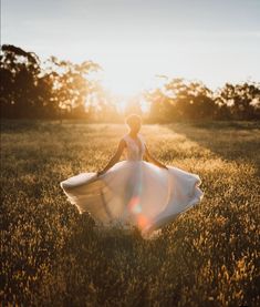 a woman in a white dress is walking through the grass