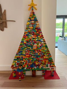 a christmas tree made out of legos in a living room next to a wall