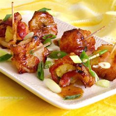 chicken skewers with pineapples and onions on a white plate