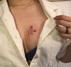 a woman's chest with a small flower tattoo on her left breast and the word love written in red ink