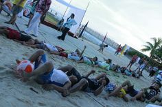 several people laying on the beach with one person holding a ball