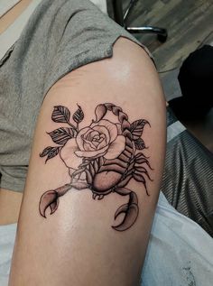 a woman's arm with a rose and scorpion tattoo on the left side of her arm