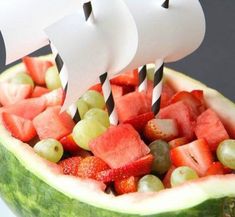 a watermelon boat with strawberries and grapes in it