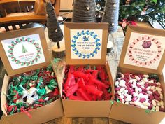 three boxes filled with different types of christmas candies on top of a wooden table