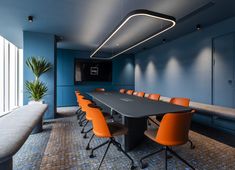 an empty conference room with orange chairs and a black table in the center, along with blue walls