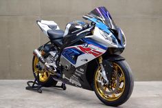 a motorcycle parked in front of a wall on the side of a road with yellow and blue rims