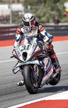 a man riding on the back of a motorcycle down a race track