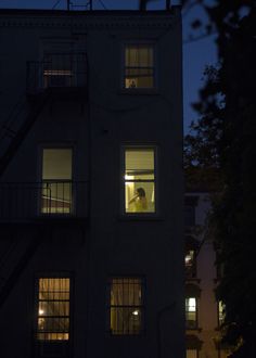 a person standing in the window of an apartment at night