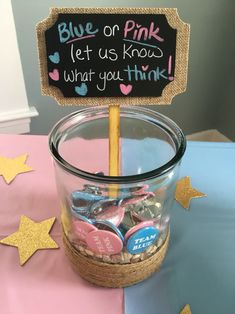 a glass jar filled with pink and blue candies next to a sign that says, blue or pink let us know what you think