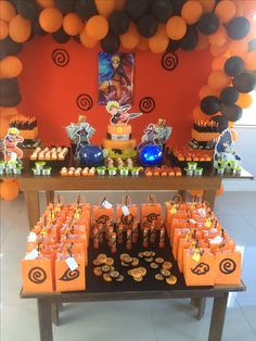 an orange and black dessert table with cupcakes, candy bars, and decorations