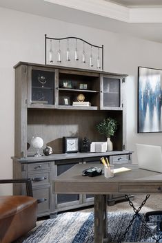 a desk with a laptop on top of it in front of a bookcase and wine glasses