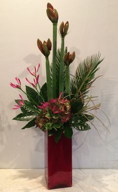 a red vase filled with green and pink flowers