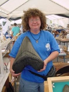 a woman is holding a large shoe in her hands