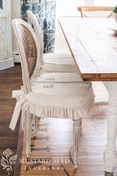 a dining room table with two chairs and a window in the backround behind it