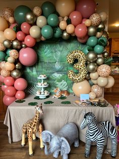 an animal themed birthday party with balloons and jungle animals on the table in front of it