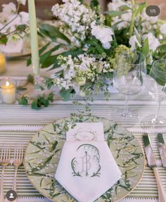 the table is set with white and green flowers, silverware, and napkins