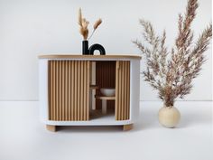 a vase with some dried plants in it next to a small cabinet that is made out of plywood