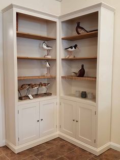 two white cabinets with birds on them in a room that has tile floors and walls