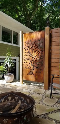 a large metal tree on the side of a building next to a fire pit and chair