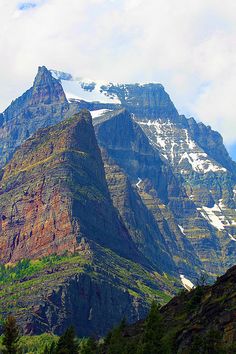 the mountains are covered in snow and green trees