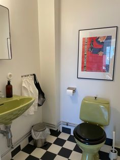 a bathroom with black and white checkered flooring, green toilet and sink in it