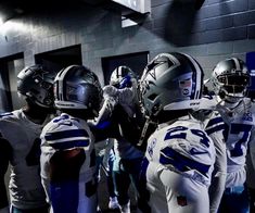 a group of football players standing next to each other in a locker room with helmets on