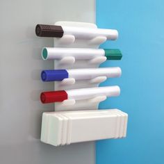 four different colored toothbrushes are attached to a wall mounted holder on a blue and white wall