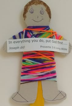 a paper doll made to look like a man with colorful yarn on his arms and legs