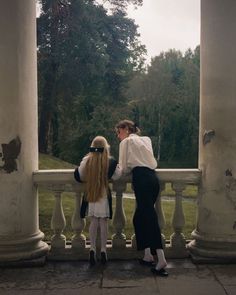 two women are standing on a balcony and one is holding the other's hand