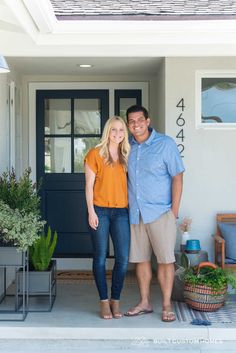 a man and woman standing in front of a house