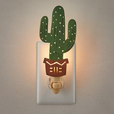 a light switch cover with a cactus head on it's face and lights in the shape of a house