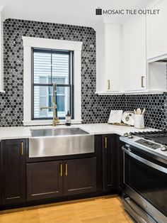 a kitchen with black and white tiles on the walls, wood flooring and stainless steel appliances