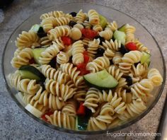 pasta salad with cucumbers, tomatoes, olives and peppers in a glass bowl