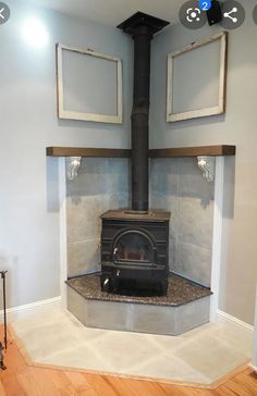 an old fashioned stove in a room with wood flooring and two framed pictures on the wall