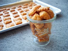 a glass jar filled with fried food next to a pan of waffles