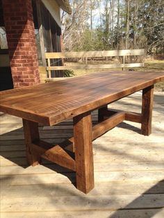 a large wooden table sitting on top of a wooden deck next to a brick building