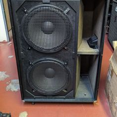 two speakers sitting next to each other on top of a shelf in a room filled with boxes