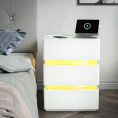 a bed with a laptop on top of it next to a night stand and nightstand