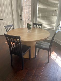 a wooden table with chairs around it in front of a white door and some windows