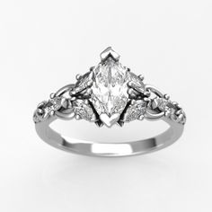 a white gold engagement ring with an intricate design on the band and a pear shaped center stone