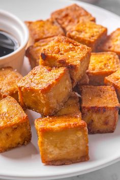 there are many pieces of bread on the plate with dipping sauce in the bowl next to it