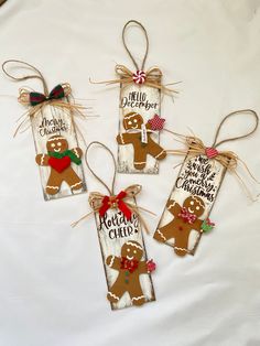 three wooden christmas tags with gingerbreads tied to them on top of a white sheet